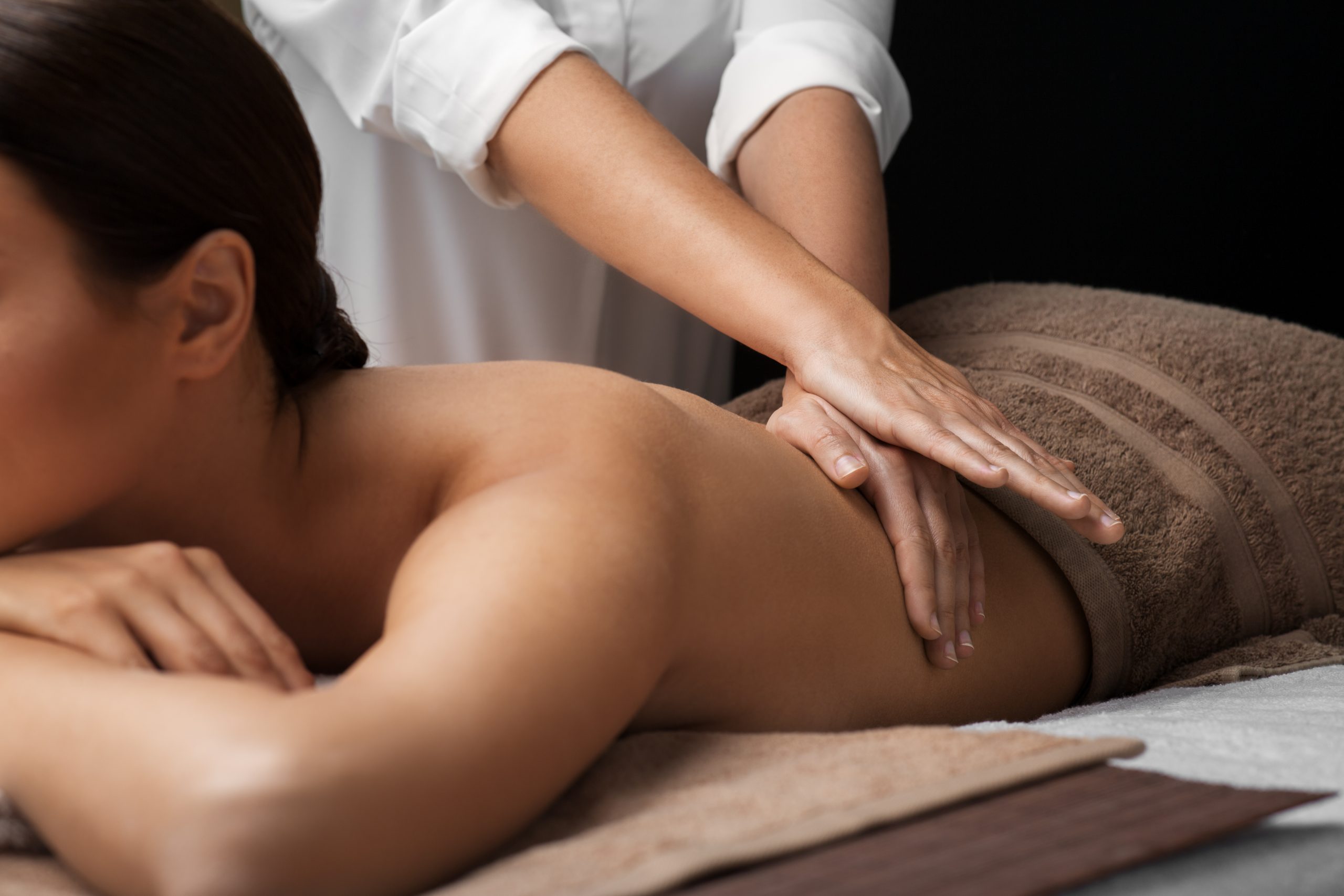 woman lying and having back massage at spa